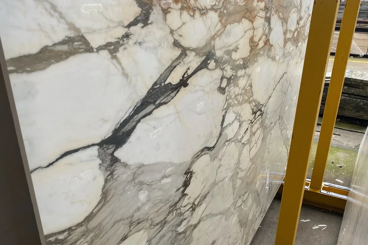 Tablero pulido de piedra blanca con vetas grises y ocres apoyado en un caballete de almacén
