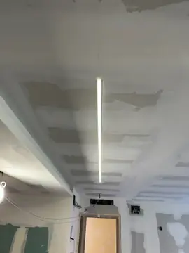 Techo de placa con línea de luz. Falso techo de placa con juntas emplastecidas y perfil de luz lineal encastrado, antes de pintar.