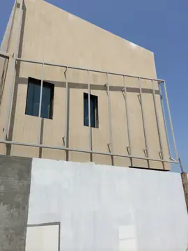 Fachada aplacada con bastidor metálico. Fachada en tono arena con dos huecos de ventana y un bastidor metálico anclado delante del aplacado.