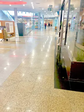 Pasillo comercial con pavimento pulido. Galería comercial con pavimento pulido en piezas moteadas y grises que refleja la luz a lo largo de los escaparates.