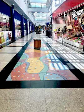 Alfombra de colores en el pavimento. Motivo de colores con formas onduladas encastrado en el pavimento del pasillo y enmarcado por una banda negra.