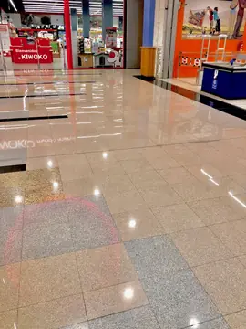 Pavimento pulido ante los locales. Pavimento pulido con paños de piezas claras, grises y moteadas y bandas negras delante de dos accesos comerciales.