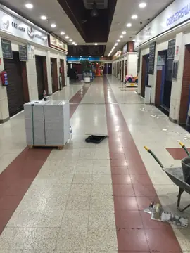Palé de losas antes de la sustitución. Palé de losas grises moteadas sobre el pavimento antiguo del pasillo, con carretilla y llanas preparadas para la sustitución.