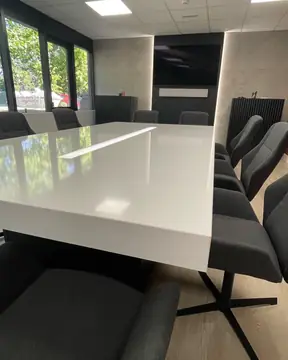 Mesa de reuniones con sobre blanco. Sobre blanco pulido de canto grueso con franja central, en una sala de reuniones.