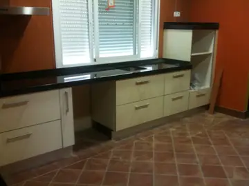 Cocina con encimera negra recién colocada. Encimera negra pulida bajo la ventana con fregadero bajo encimera, antes de montar los electrodomésticos.