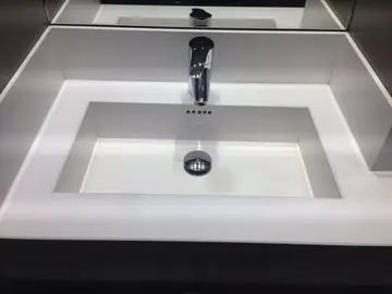 Lavabo integrado en encimera blanca. Lavabo rectangular integrado en la encimera blanca, con copete perimetral y espejo.