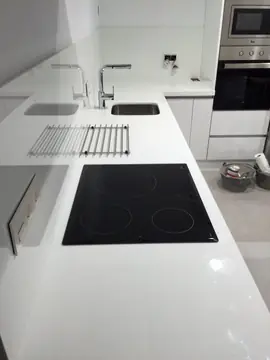 Encimera blanca con placa y senos bajo encimera. Encimera blanca pulida con placa, senos bajo encimera y frontal a juego.