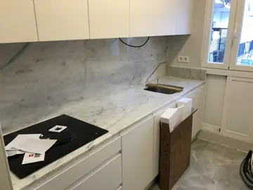 Encimera y frontal blancos con veta gris. Cocina con encimera y frontal blancos con veta gris recién colocados, con la placa y el fregadero aún por rematar.