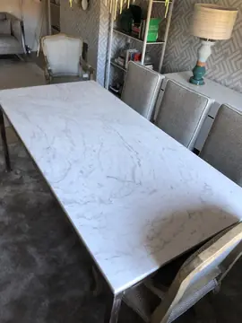 Tablero blanco veteado de mesa de comedor. Vista de cerca del tablero blanco con veta suave de la mesa de comedor, ya con sus sillas.