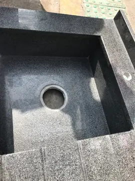 Detalle del seno del fregadero gris. Detalle del seno y el escurridor ranurado de un fregadero en pieza gris moteada.