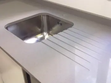Fregadero bajo encimera con escurridor. Fregadero de acero bajo encimera gris con escurridor ranurado en la propia encimera.