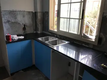 Encimera negra con fregadero doble. Encimera negra pulida con fregadero doble de acero, antes de revestir la pared.