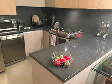Encimera y frontal en gris oscuro. Cocina con encimera y frontal a juego en gris oscuro, ya en uso.