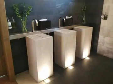 Lavabos de pie en tono crema. Lavabos de pie de volumen rectangular en tono crema, en fila e iluminados desde el suelo.