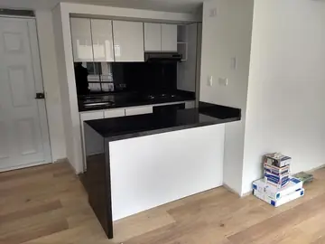 Cocina con encimera negra y península. Encimera negra pulida en una cocina blanca, con península y faldón lateral del mismo material hasta el suelo.