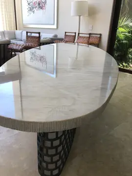 Tapa pulida con canto texturizado. Superficie pulida blanca con vetas beige y canto con acabado rayado, sobre la base de celosía metálica.