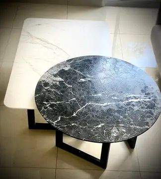 Mesas de centro en negro y blanco. Mesas bajas a distinta altura: tapa redonda negra con veta blanca sobre tapa rectangular blanca veteada.