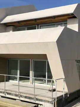 Aplacado terminado en volumen de fachada. Volumen de fachada en voladizo revestido con piezas grandes en tono crema de juntas finas sobre el ventanal de la terraza.