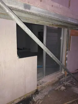 Aplacado recortado junto a un ventanal. Pieza del aplacado recortada en L para rematar junto a un ventanal, con un tubo del andamio en diagonal delante.