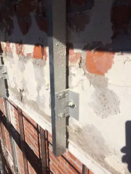 Escuadra de anclaje atornillada. Perfil vertical unido al muro con escuadra y tornillo sobre el paramento reparado con mortero.