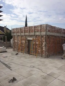 Casetón de cubierta con perfiles. Volumen de ladrillo en la azotea con la subestructura metálica montada y escaleras de obra apoyadas.