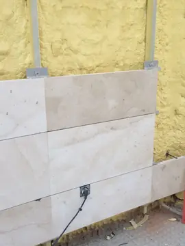Aplacado con caja eléctrica encastrada. Piezas en tono crema con veta suave colocadas sobre el aislamiento, con una toma eléctrica integrada.