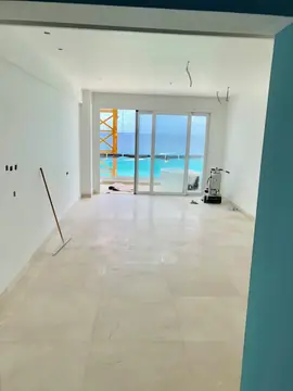Estancia con pavimento en tono crema. Habitación con pavimento pulido en tono crema con vetas, rodapié a juego y ventanal al mar, a falta de retirar la pulidora.