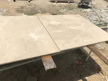 Piezas en tono crema con canto redondeado. Dos piezas en tono crema con vetas claras y canto redondeado sobre un caballete en el patio de trabajo.