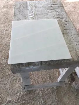 Pieza blanca pulida sobre banco de trabajo. Pieza blanca pulida apoyada sobre un banco de madera en la obra.
