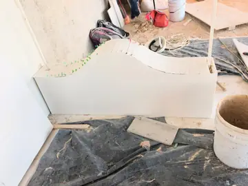 Frente con remate ondulado en montaje. Montaje de un frente blanco con coronación ondulada hecha con tiras de piezas blancas, sujetas con cuñas de colocación.