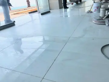 Pulido del pavimento blanco. Pavimento blanco en piezas grandes recién pulido, con la pulidora a un lado y el mar al fondo.