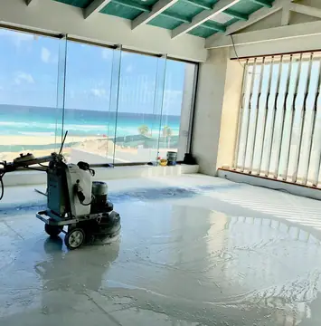 Pulido de pavimento frente al mar. Pulidora trabajando el pavimento claro en una sala acristalada con vistas al mar.