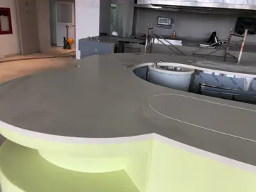 Encimera curva con pila redonda. Detalle de la encimera clara de formas curvas con pila redonda y frente verde, con la cocina en obra detrás.