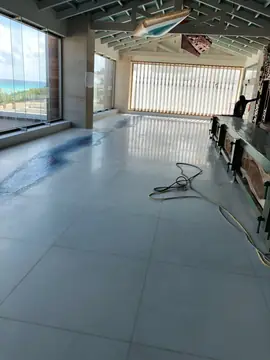 Galería con pavimento pulido y barra en montaje. Pavimento pulido con mosaico azul en una galería acristalada, con una barra en montaje junto a la pared.