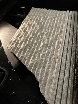 Acabado labrado en estrías. Detalle de una pieza de piedra beige con la cara labrada en estrías verticales y el canto partido.