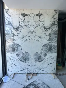 Piezas casadas en espejo sobre calzos. Piezas blancas con veta gris oscura casadas en espejo, apoyadas sobre calzos de madera durante el montaje.