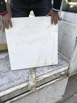 Pieza blanca veteada sobre el camión. Un operario sostiene una pieza blanca con vetas grises y ocres sobre la caja del camión.