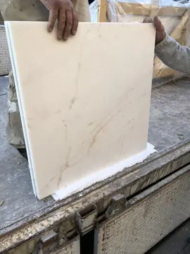 Pieza blanca con vetas ocres a la descarga. Pieza blanca con vetas ocres finas sujeta sobre la caja del camión, con los caballetes de madera del transporte detrás.