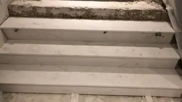 Peldaños blancos en colocación. Peldaños con huella y tabica en piezas blancas, con el escalón superior aún en bruto.