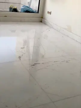 Pavimento pulido con rodapié a juego. Suelo de piezas blancas pulidas con vetas grises y rodapié a juego junto al ventanal.