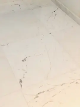 Detalle de veta gris en el pavimento. Primer plano de piezas blancas pulidas con vetas grises finas y juntas estrechas.