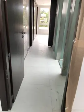 Pasillo con pavimento blanco en obra. Pasillo con suelo blanco veteado en piezas grandes, puertas oscuras y protecciones de papel aún colocadas.