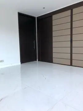 Suelo blanco ante puertas oscuras. Pavimento blanco veteado en gran formato ante una puerta oscura y un armario de paneles en tono arena.