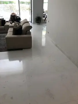 Salón amueblado con suelo blanco. Pavimento blanco pulido en piezas grandes con rodapié a juego, ya con el salón amueblado.