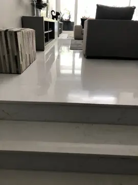Escalones de acceso al salón. Peldaños blancos que suben a un salón con pavimento pulido en piezas grandes.