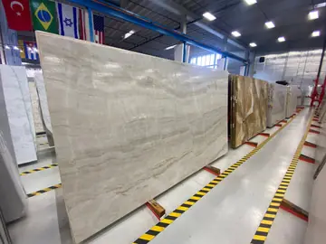 Tablero crema de veta horizontal. Tablero pulido en tono crema con vetas horizontales suaves, expuesto en caballete junto a otros tableros.