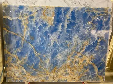 Tablero azul con vetas doradas de frente. Tablero pulido de fondo azul con vetas doradas y blancas, visto de frente en su caballete de exposición.