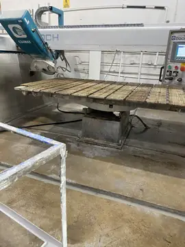 Mesa de la cortadora de puente. Cortadora de puente con la mesa de listones vacía y un carro metálico en primer plano.