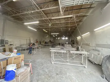 Nave de elaboración de encimeras. Nave de trabajo con encimeras sobre carros metálicos y operarios rematando piezas al fondo.