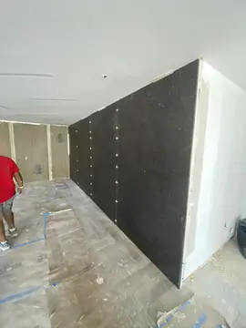 Pared negra recién revestida. Pared revestida con piezas negras de gran formato, con los separadores aún en las juntas y el suelo protegido.
